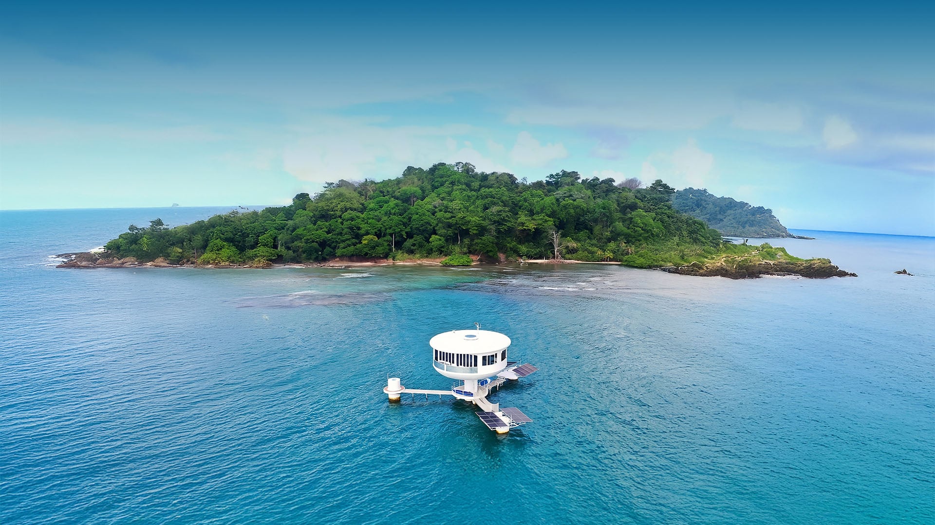 A SeaPod floating home on the ocean beside a tropical island